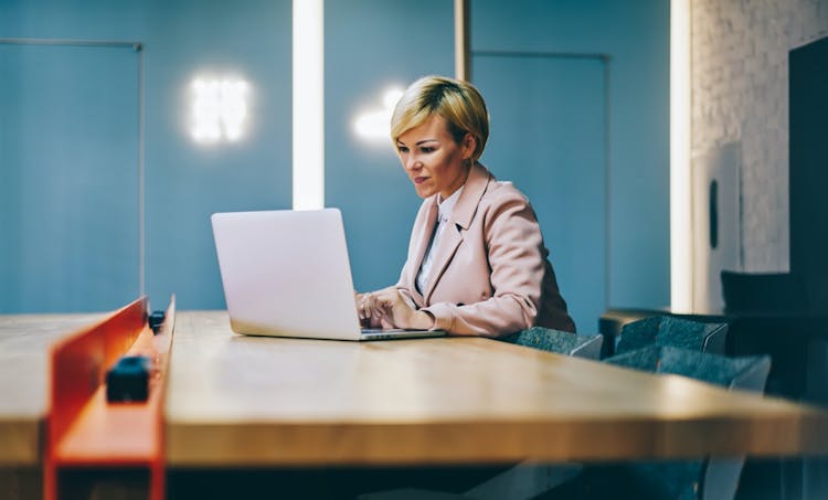 Blond woman working at a laptop at a counter