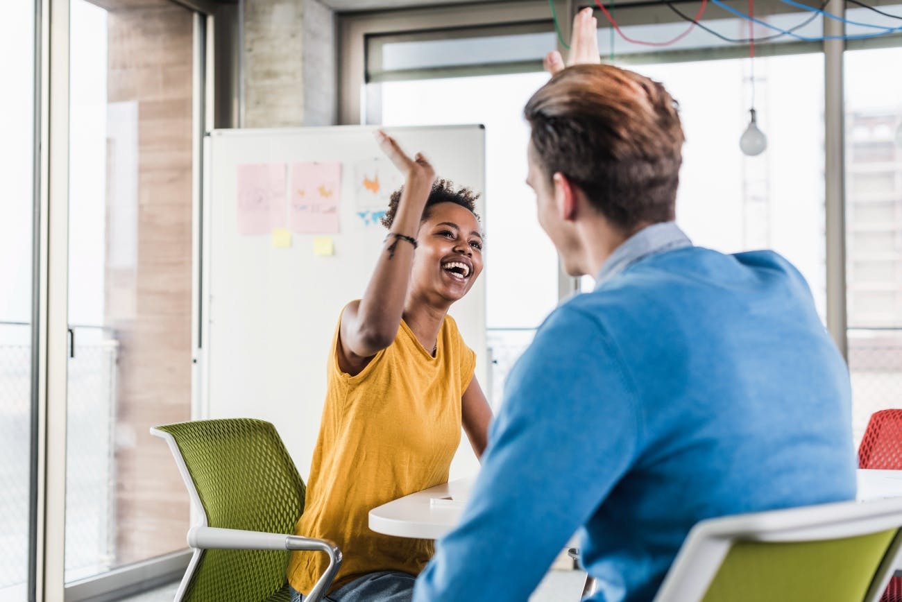 Man and woman colleagues high-five at table