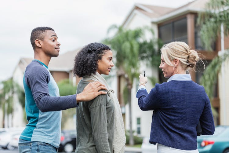 Young couple viewing buildings with real estate agent 