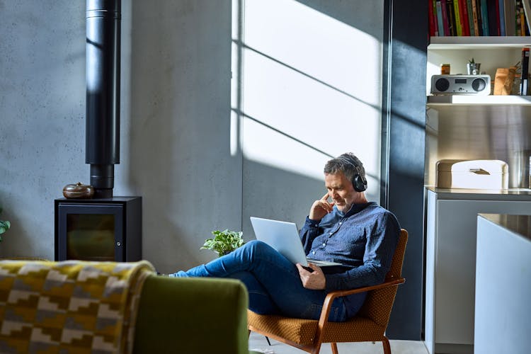 Man in lounge chair using laptop with headphones