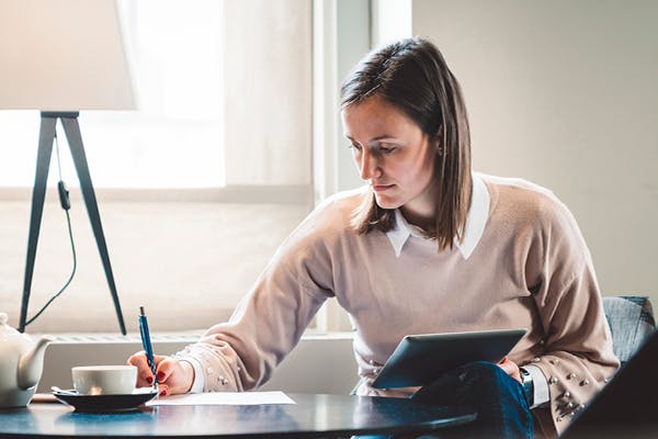 Woman with tablet taking notes next to lamp