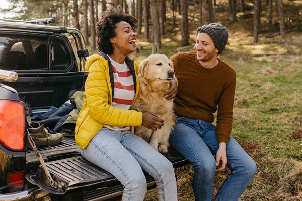 Couple with dog sitting on truck flatbed