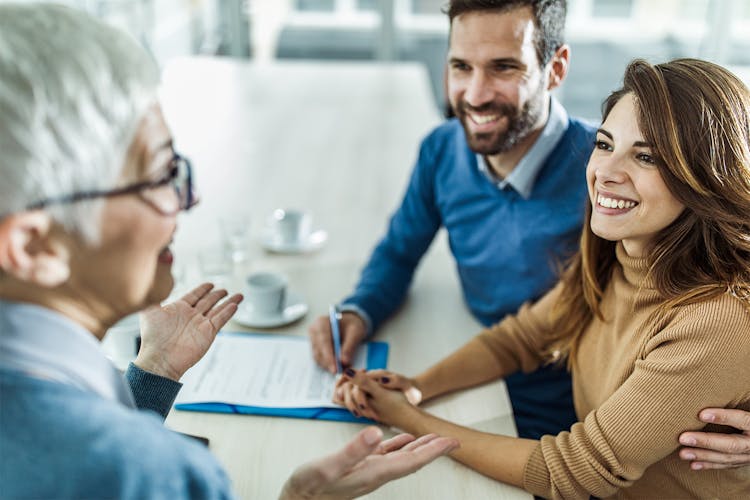 Smiling couple talking to a woman in an office