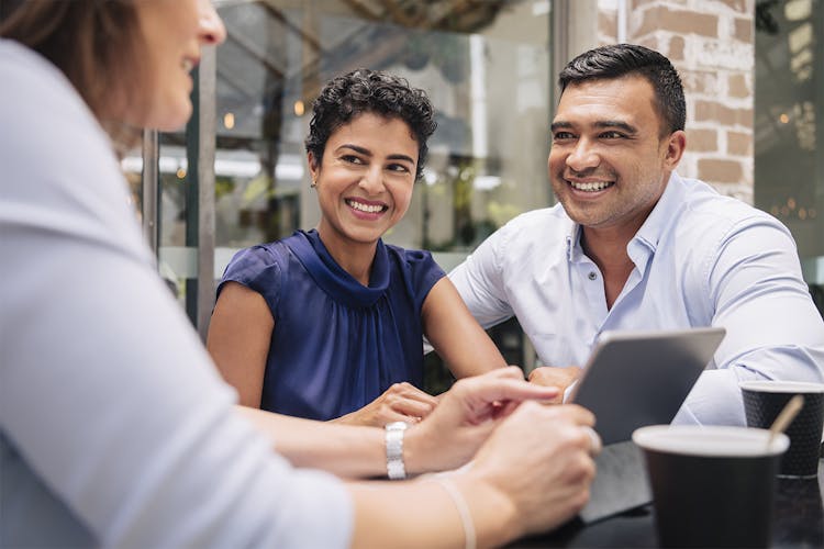 Smiling couple with agent at cafe table