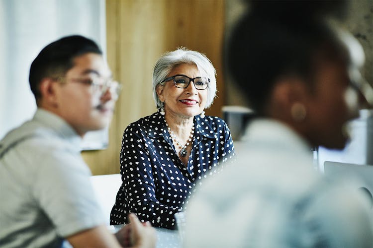 Smiling white-haired Latinx woman in a meeting