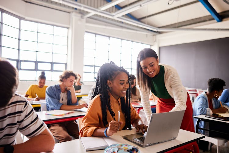 Teacher working with high school student at desk