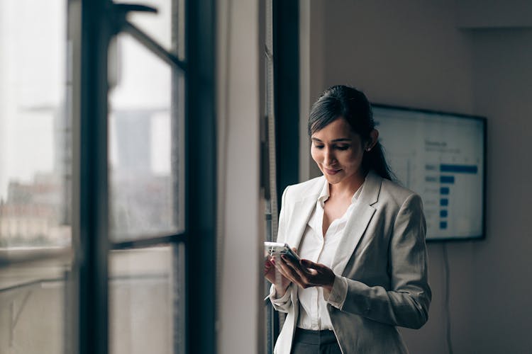 Woman wearing a suit looking at a cell phone in a conference room