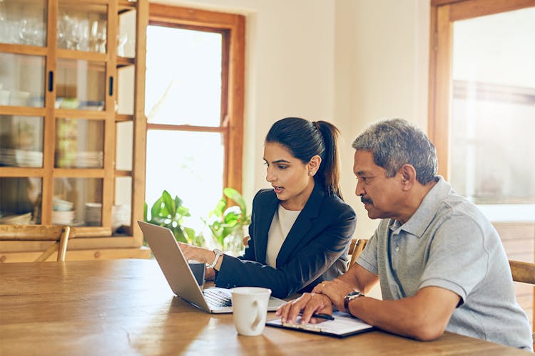 Young woman showing older man something on a laptop