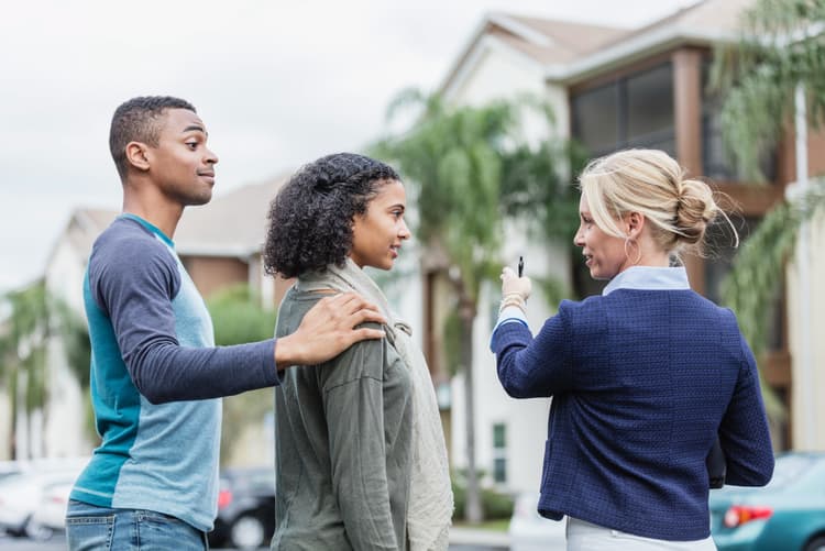 Young couple viewing buildings with real estate agent