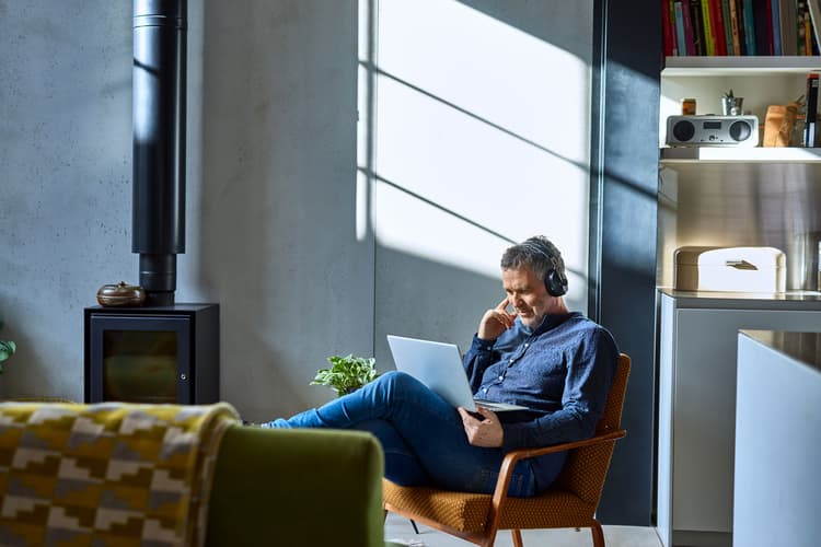 Man in lounge chair using laptop with headphones Man in lounge chair using laptop with headphones