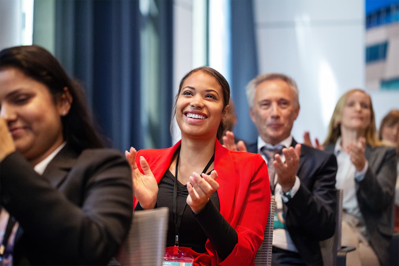 People in a classroom applauding and looking toward the speaker People in a classroom applauding and looking toward the speaker