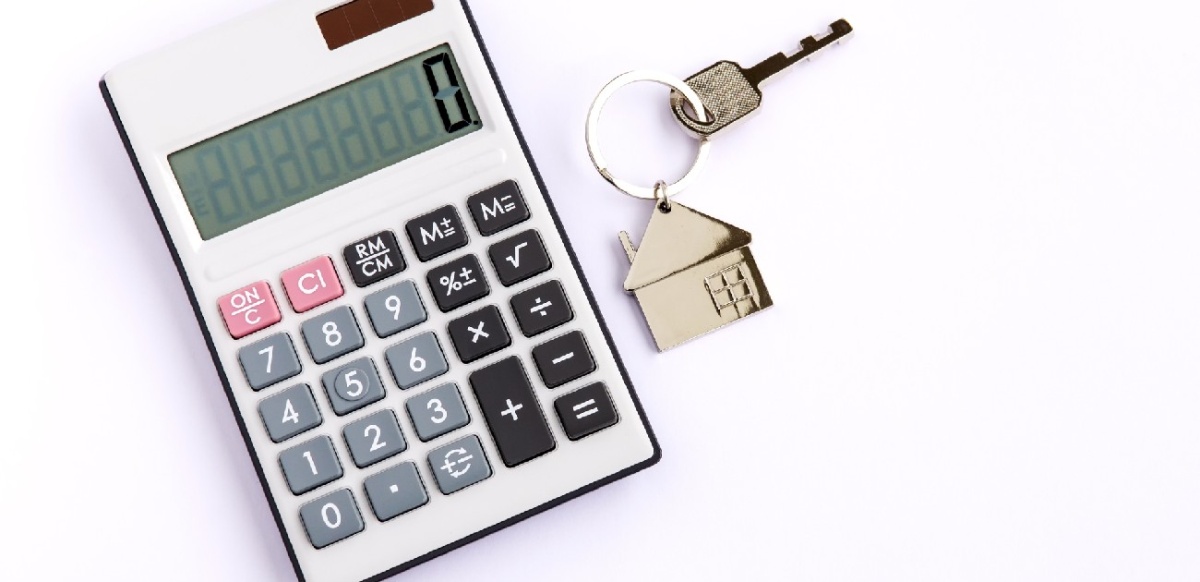 A picture of a calculator and a key with a house keychain on a white background.